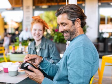 Smiling man pays with smartphone.